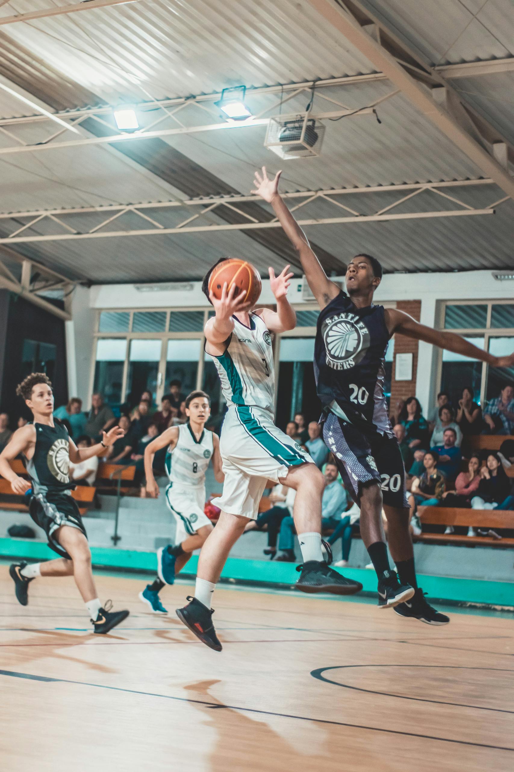 Intense basketball match with players in action on an indoor court.